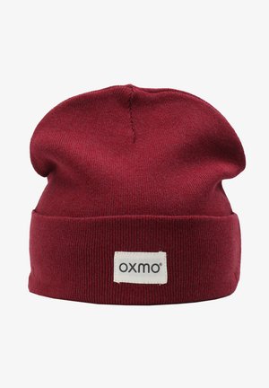 Rød strikket beanie-hat med opfoldet kant og et vævet mærke, der viser brandnavnet "oxmo", med en glat tekstur og rund top.