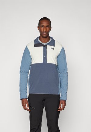 Pullover leggero con un design a blocchi di colore blu e bianco, dotato di chiusura a bottoni a pressione, alto colletto e morbida texture del tessuto.