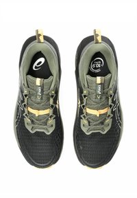Schwarze und olivgrüne Sportschuhe verfügen über ein Obermaterial aus Netzgewebe, eine Gummisohle, gelbe Akzente und ein schnürbares Design mit verstärkten Fersenschlaufen.