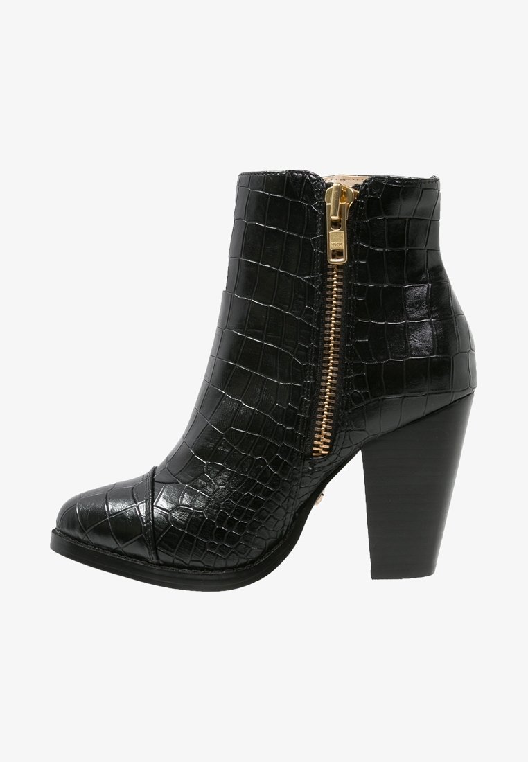 Bottine noire en cuir à texture crocodile avec fermeture éclair dorée et talon haut carré empilé.