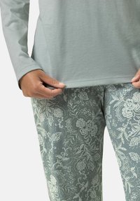 Ljusgrön långärmad topp ihop med mönstrade tealbyxor med blommönster i ljusare nyanser och fina detaljer.