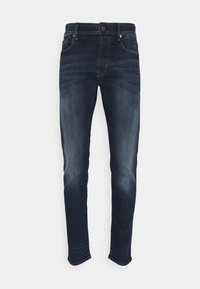 Tumsininen farkut slim-fit-mallilla, joissa on hienovarainen haalistus, viisi taskua ja nappikiinnitys. Pintakuvio on sileä, ja varusteet ovat vähäiset.