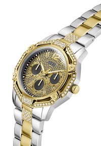 Guld- og sølvfarvet ur med oktagonal kasse, tekstureret gulddial, tre sub-dials og krystalaccentuer på bezel og båndled.