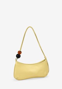Bolso de piel amarillo con forma curva, que presenta una delgada correa para el hombro y cuentas decorativas redondas en ámbar y negro.