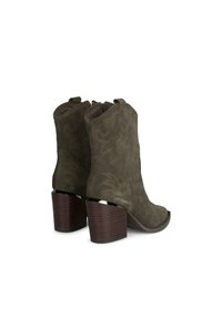 Botas de tobillo de ante marrón con un tacón ligeramente más ancho, costuras decorativas y cierre de cremallera. Superficies texturizadas con un diseño de punta afilada.