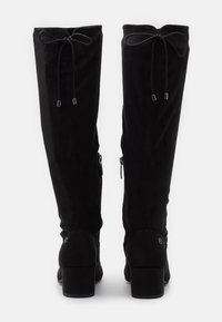 Bottes noires en daim à hauteur de cuisse avec une fermeture à liens en haut, des zips sur les côtés et un talon large. Texture lisse et forme ajustée.