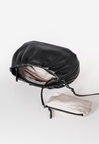 Schwarze Lederhandtasche mit gerafftem Design. Sie verfügt über ein helles, gemustertes Futter und eine kleine, passende Tasche mit Reißverschluss.