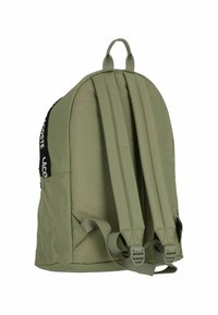 Mochila de tela verde con tres correas acolchadas, un asa superior y un acento de logo negro. Presenta una forma redondeada y hebillas laterales ajustables.