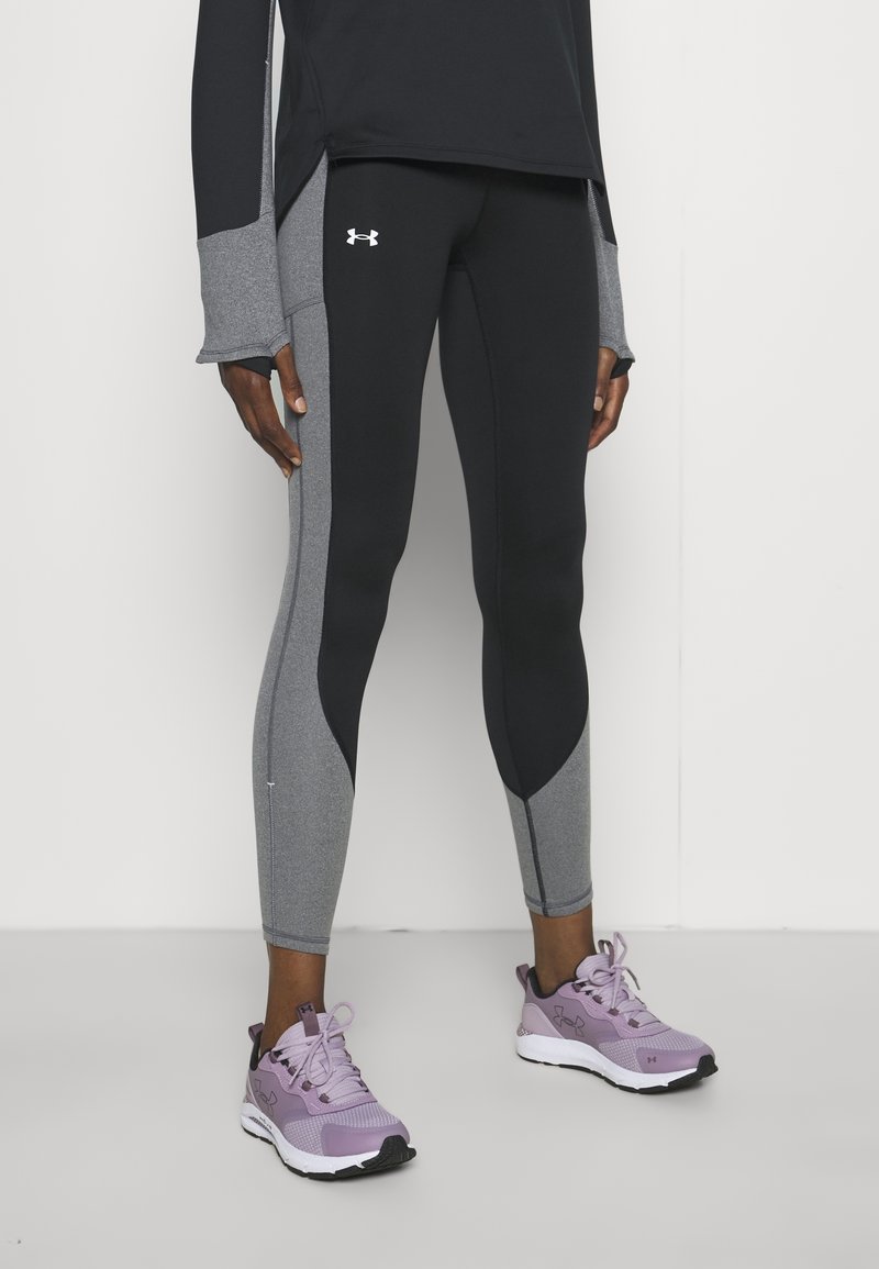 Svarta och grå tajta leggings med en elegant design, som har kontrasterande paneler. Bärs med lavendelfärgade träningsskor.