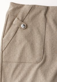 Pantalon en laine beige avec un motif chevron, poches avant et accent en bouton argenté à la taille. Surface du tissu texturée.