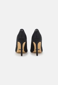 Scarpe nere con tacco alto in tessuto strutturato, decorate con piccole borchie. Presentano una punta a stilo e un tacco a spillo, con un logo di marca.