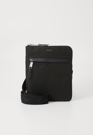Zwarte nylon schoudertas met een textuur oppervlak, ritssluiting, voorzak en verstelbare strap. Bevat subtiele branding aan de voorkant.