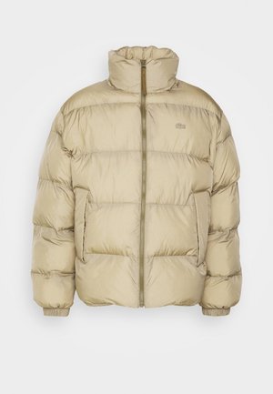 Chaqueta de abrigo en beige claro con cuello alto, cremallera frontal de longitud completa, puños elásticos y bolsillos laterales. Confeccionada con una tela brillante y suave.