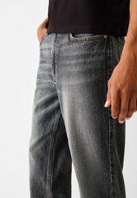 Mörkgrå denimjeans med en blekt finish, femfickorsdesign, raka ben och synliga sömnadsdetaljer.