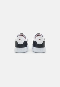 Black and white sneakers feature a smooth leather upper, a lightweight rubber sole, and a small logo accent on the heel.