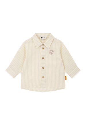 Kremowa koszula z długim rękawem w pionowe paski, z zapięciem na guziki z przodu oraz haftem z misiem na lewej piersi. Miękka bawełniana tkanina.