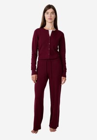 Burgundowy zestaw odzieży domowej z zapinanym kardiganem i spodniami na sznurki, z prążkowaną teksturą i pełnymi rękawami.
