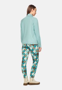 Light teal long-sleeve top paired with patterned pants featuring blue, brown, and white diamonds. Soft fabric with a smooth texture.
