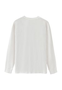 Långärmad vit skjorta av mjuk bomull. Har en avslappnad passform, rund halsringning och subtil sömdetaljering vid axlar och ärmslut.