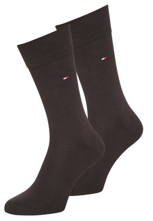 Chaussettes en mélange de coton marron avec des bords côtelés et un petit détail de logo rouge, blanc et bleu sur le côté. Texture lisse, longueur standard.