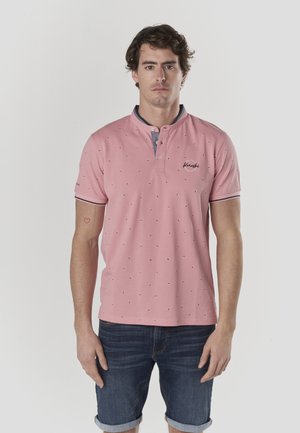 Polo de color rosa claro con mangas cortas, cuello gris, detalles en negro y un patrón pequeño repetido. Logotipo bordado en el pecho.