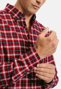 Rot-weißer Karomuster-Hemd mit schwarzem Akzent, ausgestattet mit einem Kragen, langen Ärmeln und einem taillierten Schnitt, der einen strukturierten Stoff präsentiert.