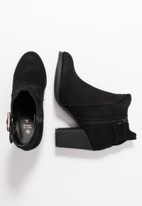 Zwarte suède enkellaarsjes met een dikke gestapelde hak, ritssluiting aan de zijkant en een gebogen ontwerp. De binnenkant is voorzien van een merkvoering.