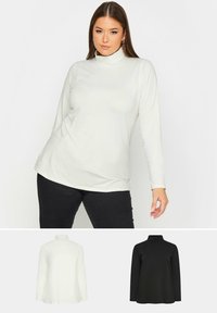 Långärmad polotröja i kräm och svart, tillverkad av ett mjukt tyg med en figurnära design och ribbat mönster vid kragen.