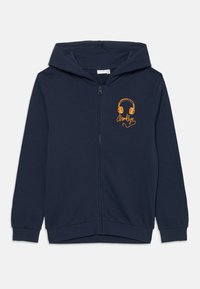 Mørkeblå zip-up hættetrøje lavet af blødt stof, med en frontlynt, en hætte, og et gult grafisk motiv af hovedtelefoner med teksten "Brooklyn".