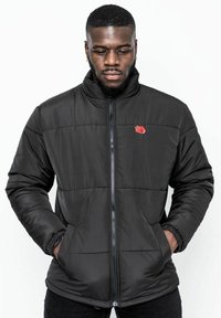 Svart vadderad jacka med hög krage, dragkedjestängning och röd ros broderi. Har sidofickor och en slät, glänsande finish.