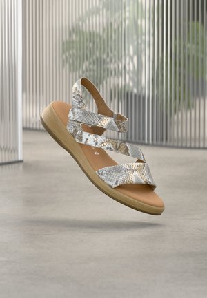 Basutės su dirželiais, su gyvatės odos raštu pilkšvų ir baltų atspalvių, su ruda gumine padu ir paminkštinta vidpadžiu, suteikiančiu atramą.