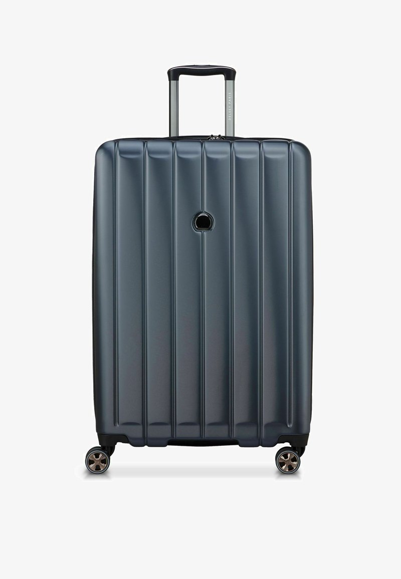 Valise rigide de couleur bleu foncé avec un design à rainures verticales, poignée rétractable et quatre roues pivotantes pour une maniabilité aisée.