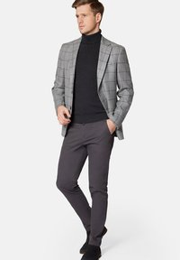 Szary marynarka w kratę na czarnym golfie, zestawiona z ciemnoszarymi spodniami slim fit i czarnymi butami. Gładki materiał o zorganizowanej strukturze.