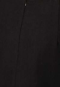 Svart ulltyg med en slät textur. Har en subtil lyster och en central söm, med en dragkedjedetalj högst upp. Enkelt design.