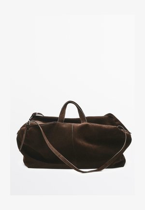 Brązowa zamszowa torba typu duffle z dwoma górnymi uchwytami i długim paskiem na ramię; cechuje się gładką fakturą i zamknięciem na zamek.