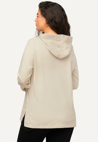 Felpa beige con tasca a marsupio, vestibilità comoda e spacchi laterali. Realizzata in un morbido tessuto con cappuccio accogliente.