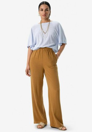 Light blue oversized t-shirt, relaxed fit; mustard yellow wide-leg pants with elastic waistband; beige sandals; layered chain necklaces.