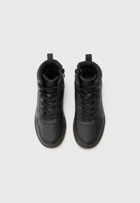 Zwarte hoge sneakers van glad leer met geperforeerde details. Voorzien van veters, een rits en een rubberen zool in een contrasterende bruine kleur.