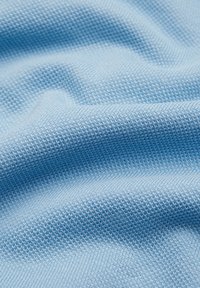 Jasnoniebieski materiał tekstylny o miękkim, teksturowanym wzorze dzianiny, ilustrujący gładki i lekko rozciągliwy materiał idealny do odzieży lub tapicerki.