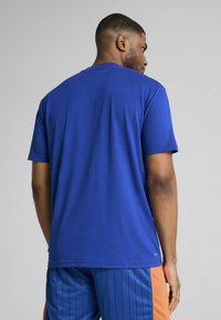 Rövid ujjú kék sportpóló, sima anyagból készült, klasszikus fazonnal és kerek nyakkivágással, látható minták vagy díszítések nélkül.