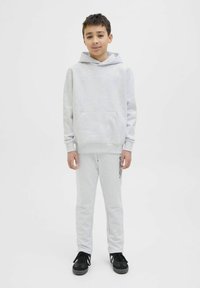 Grauer Hoodie mit Kängurutasche, kombiniert mit grauen Jogginghosen mit seitlichem Logo-Detail. Tragen mit schwarzen Sportschuhen. Minimalistisches Design.