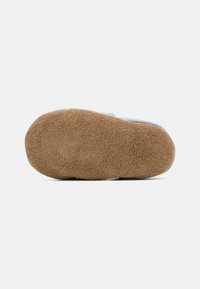 Suela de zapato de ante marrón con forma redondeada, que presenta un acabado texturizado y un borde ligeramente elevado para mejorar la tracción.