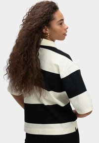 Chemise à manches courtes avec un motif rayé noir et crème. Fabriquée en coton, elle présente un col et une coupe décontractée.