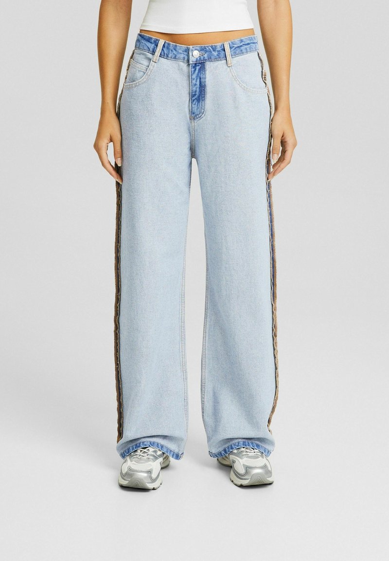 Ljust blå vida jeans i denim, med en kontrasterande blå midja och bruna texturerade sidremsor. Avslappnad passform med ofärgad fåll.