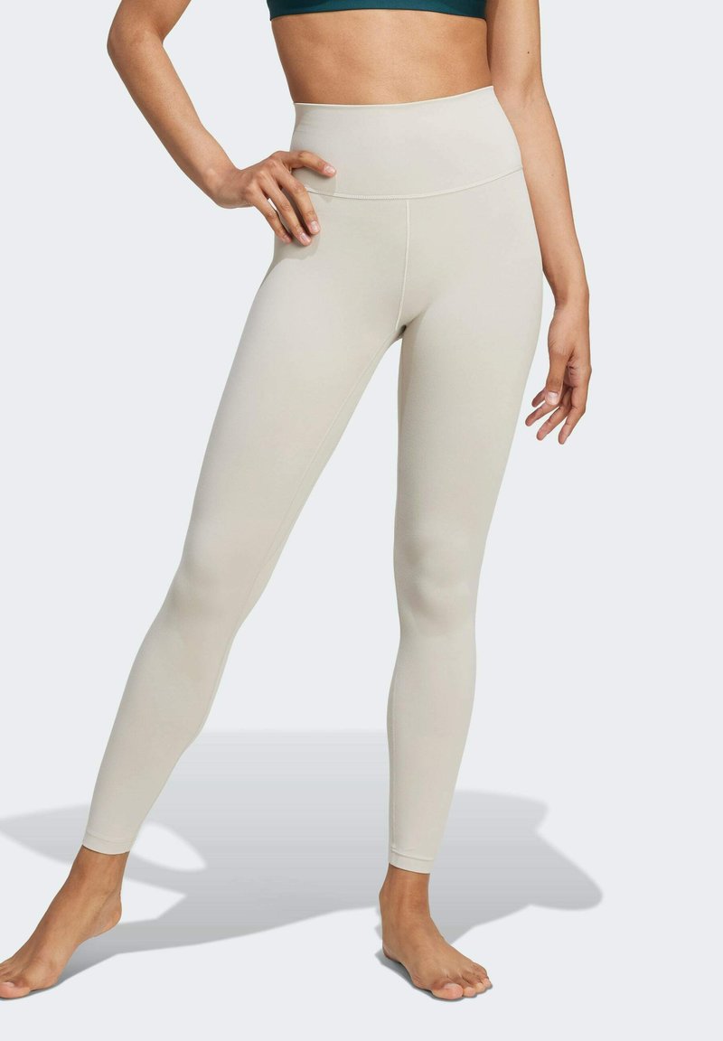 Höga, beiga leggings i ett stretchigt, slätt tyg; figurnära siluett med en enkel design utan synliga mönster eller detaljer.