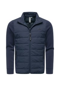 Laivastonsininen takki, jossa on pehmustettu etuosa, pehmeät hihat, vetoketjulliset taskut ja korkea kaulus. Vasemmassa yläreunassa on logotunniste.