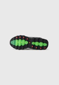 Semelle de sneaker noire avec un entre-soulier vert ondulé, des accents rouges et des motifs texturés pour l'adhérence. Fabriquée en caoutchouc durable.
