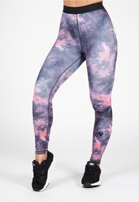 Hoge taille legging in een tie-dye patroon met tinten paars en roze. Gemaakt van rekbare stof, met een zwarte tailleband en logo.