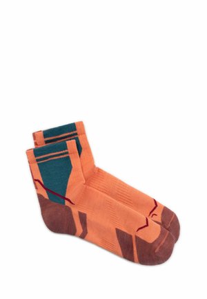 Pair of ankle-length socks in orange with brown toes and heels, featuring dark teal and red geometric patterns.