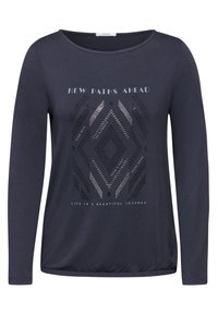 Marineblaue Langarmbluse mit rundem Ausschnitt, die ein geometrisches Muster aus silbernen Punkten und bedrucktem Text in Weiß aufweist. Elastisches Material, lockere Passform.